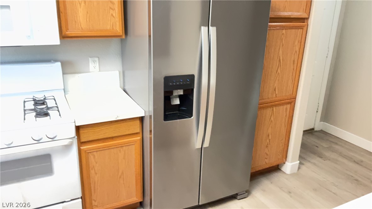 830 Carnegie Street, Unit 1024 Henderson, NV 89052 - Photo 20 of 27 Kitchen with white appliances, light countertops, light wood-style flooring, and wood finish cabinets