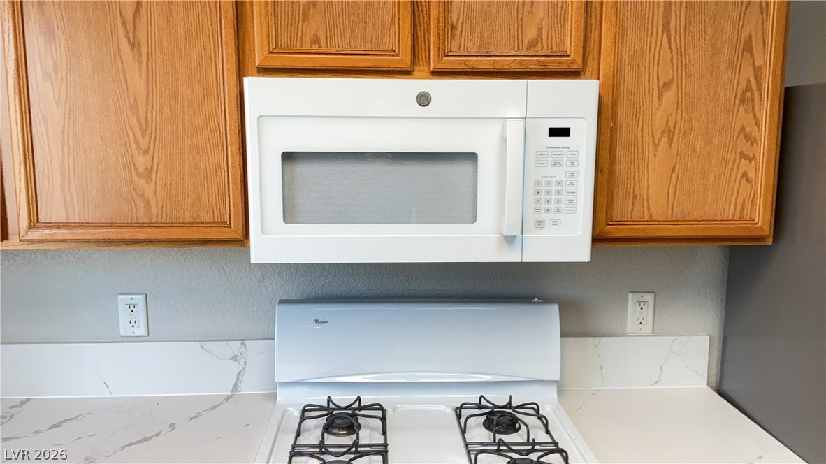 830 Carnegie Street, Unit 1024 Henderson, NV 89052 - Photo 21 of 27 Kitchen view of white appliances, wood finish cabinets, and light stone counters