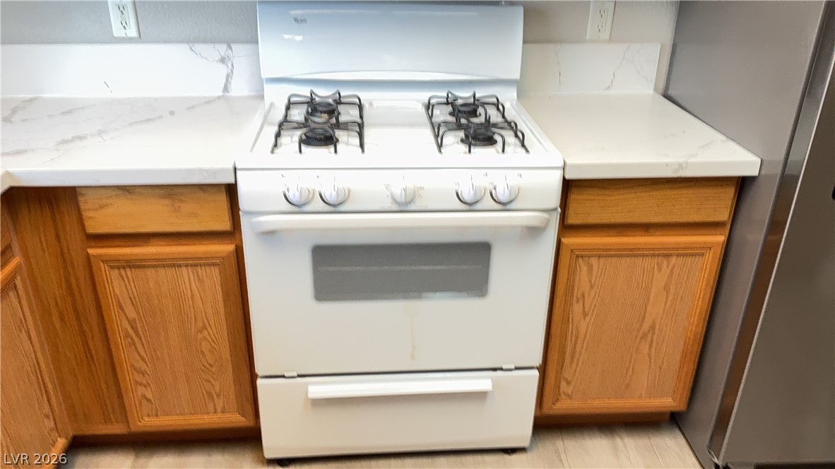 830 Carnegie Street, Unit 1024 Henderson, NV 89052 - Photo 22 of 27 Kitchen with white gas range, freestanding refrigerator, and wood finish cabinetry