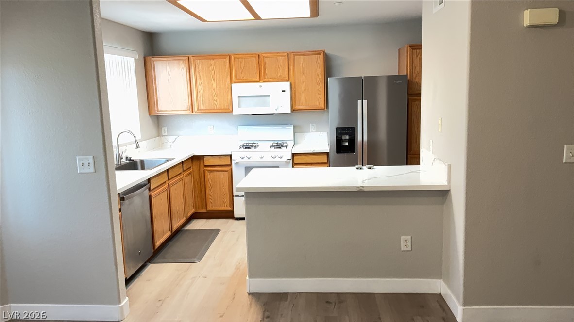 830 Carnegie Street, Unit 1024 Henderson, NV 89052 - Photo 6 of 27 Kitchen with stainless steel appliances, light countertops, a peninsula, light wood-style flooring, and wood finish cabinets