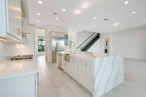 a large white kitchen with granite countertop a large window and a sink