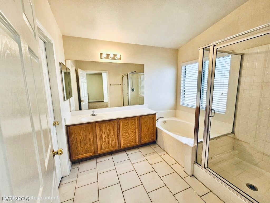 5953 Crumbling Ridge Street Henderson, NV 89011 - Photo 20 of 42 A well-lit primary bathroom featuring a spacious built-in tub and a separate glass-enclosed shower.
