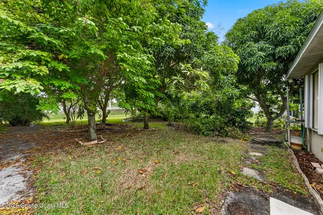 an aerial view of residential houses with outdoor space and trees