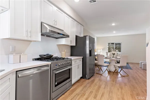 a kitchen with stainless steel appliances a stove a refrigerator cabinets and dining table