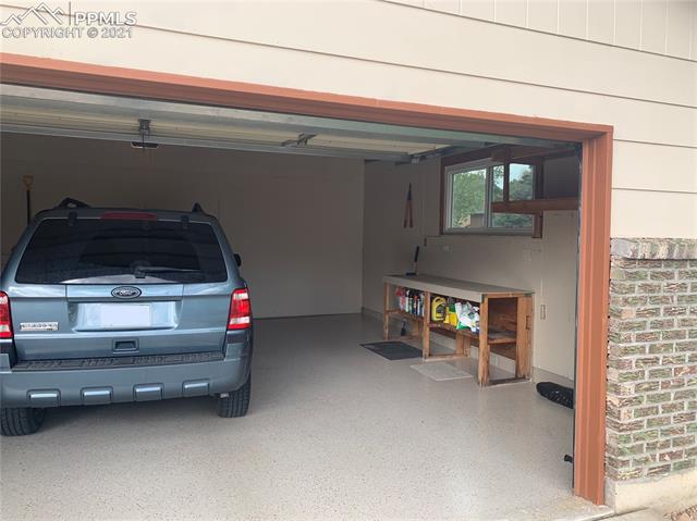 1704 Wooten Road Colorado Springs, CO 80915 - Photo 6 of 7 Extra-wide garage with epoxy coated floor, workbench, and shelving.