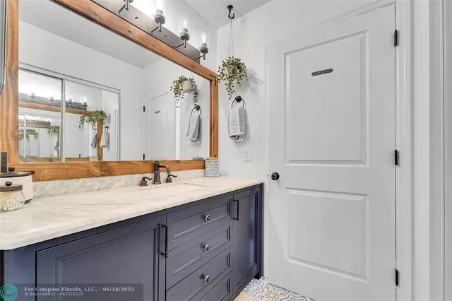 a bathroom with a granite countertop sink a mirror and a shower