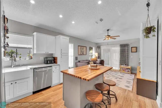 a open kitchen with stainless steel appliances granite countertop a sink dishwasher a stove a refrigerator a dining table and chairs with wooden floor