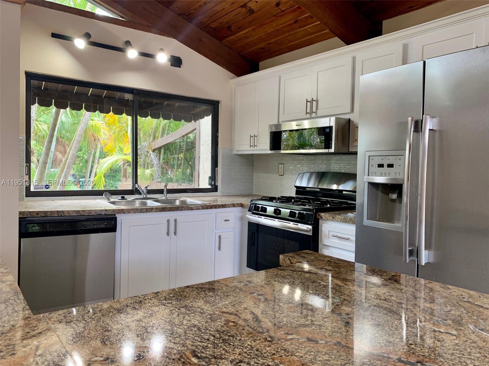 11318 Southwest 114th Cir Terrace Miami, FL 33176 - Photo 8 of 30 a kitchen with stainless steel appliances granite countertop a stove a refrigerator and a sink with wooden cabinets