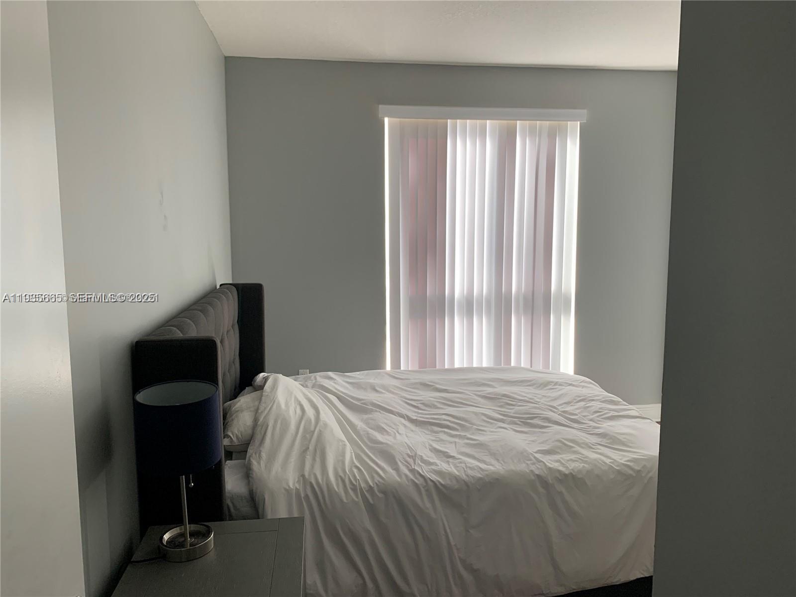 7275 Southwest 90th Street, Unit C312 Miami, FL 33156 - Photo 4 of 9 a bed sitting in a bedroom next to a window