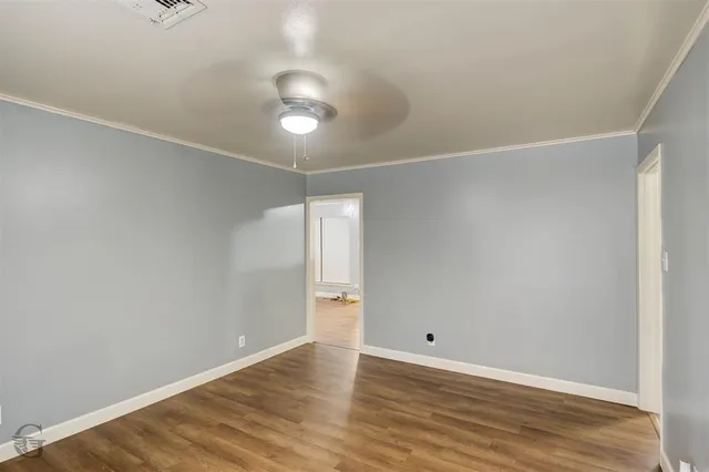 an empty room with wooden floor and ceiling fan