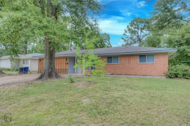 a view of a house with a yard and large tree