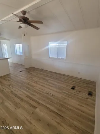 an empty room with wooden floor and windows