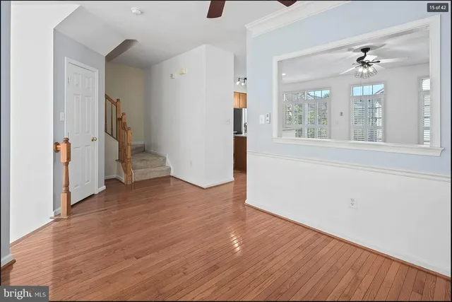 a view of empty room with wooden floor and fan