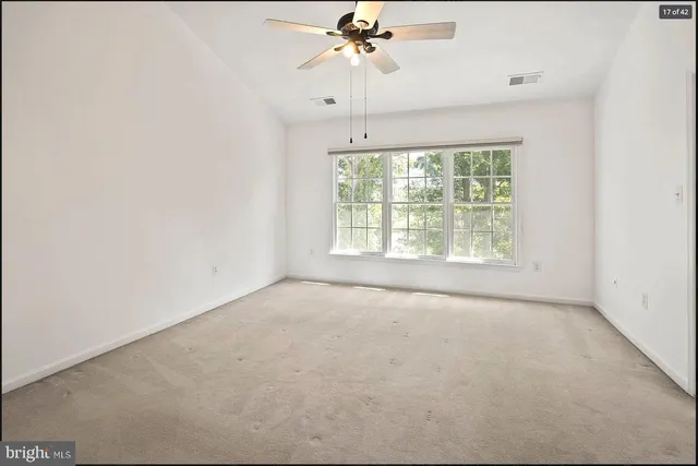 an empty room with a chandelier fan and windows