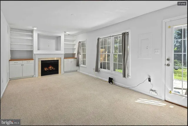 a view of an empty room with a fireplace and a window