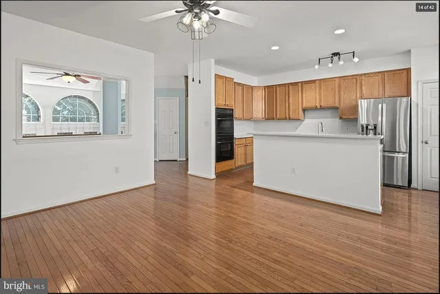 a kitchen with stainless steel appliances granite countertop a refrigerator a sink dishwasher a stove and a dining table with wooden floor