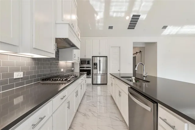 a kitchen with stainless steel appliances granite countertop a sink a stove and a refrigerator