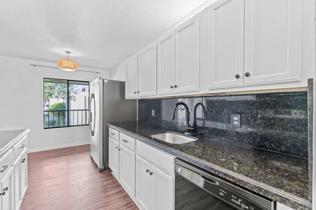 a kitchen with granite countertop white cabinets and sink