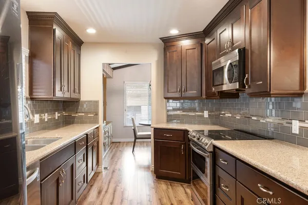 a kitchen with stainless steel appliances granite countertop a refrigerator a sink dishwasher a stove and a refrigerator with wooden floor