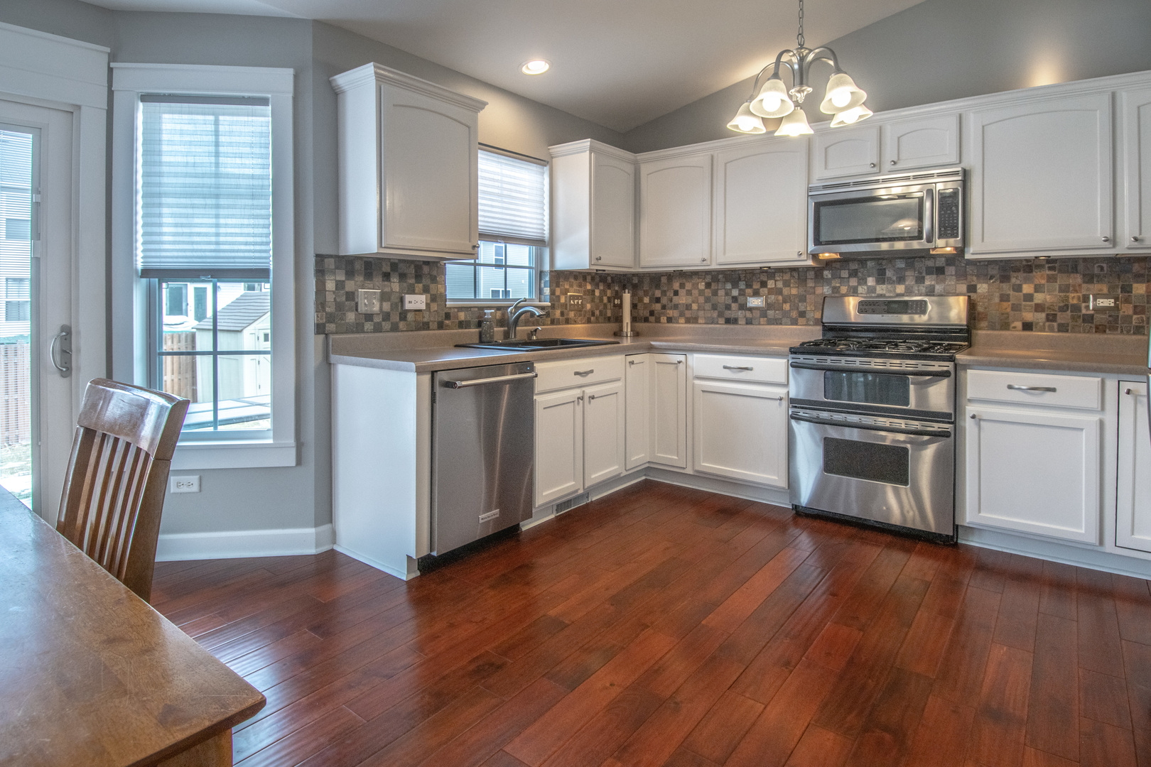 1938 Ashbrooke Road Romeoville, IL 60446 - Photo 8 of 42 a kitchen with granite countertop wooden floors stainless steel appliances and white cabinets