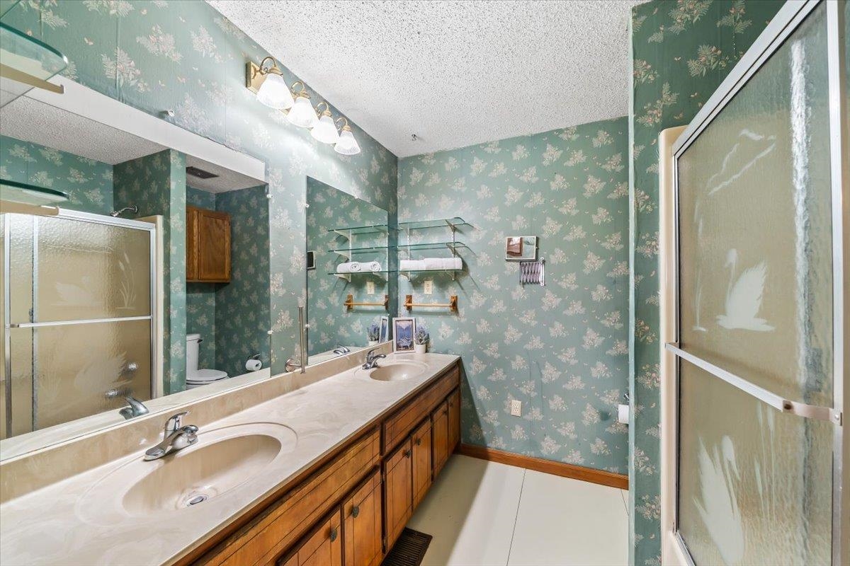 2972 Russell Bond Road Millington, TN 38053 - Photo 22 of 38 Bathroom with wallpapered walls, a stall shower, a textured ceiling, double vanity, and light tile patterned floors
