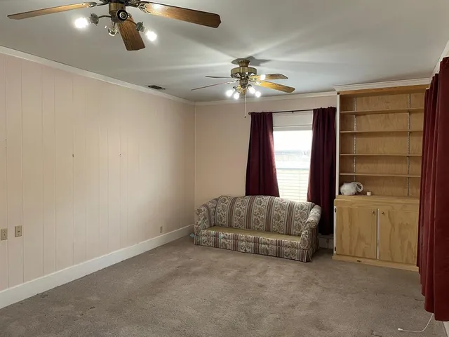 an empty room with windows and ceiling fan