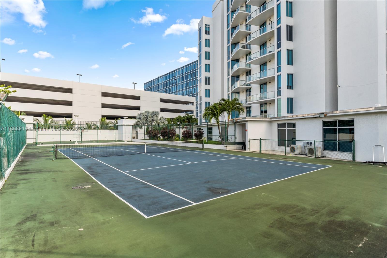 3029 Northeast 188th Street, Unit 924 Aventura, FL 33180 - Photo 18 of 20 a view of a tennis ground with large trees