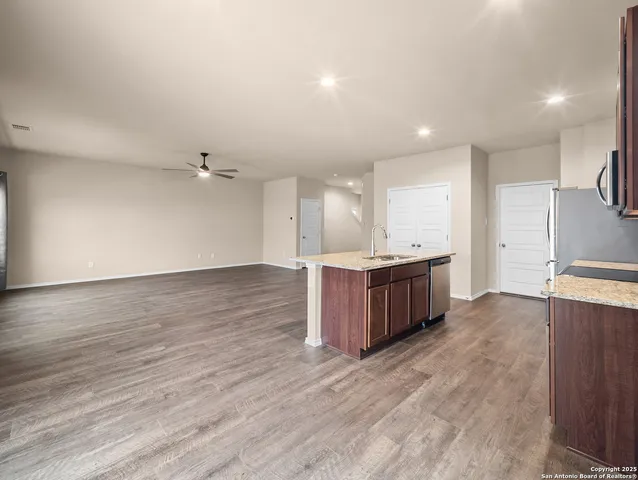 a large room with kitchen island a sink wooden floor and stainless steel appliances