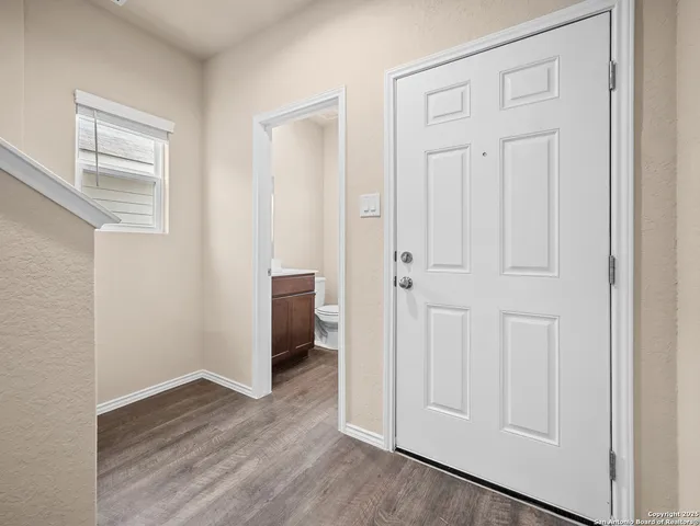 an empty room with wooden floor closet and windows