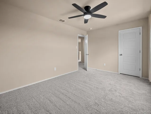 an empty room with windows and fan