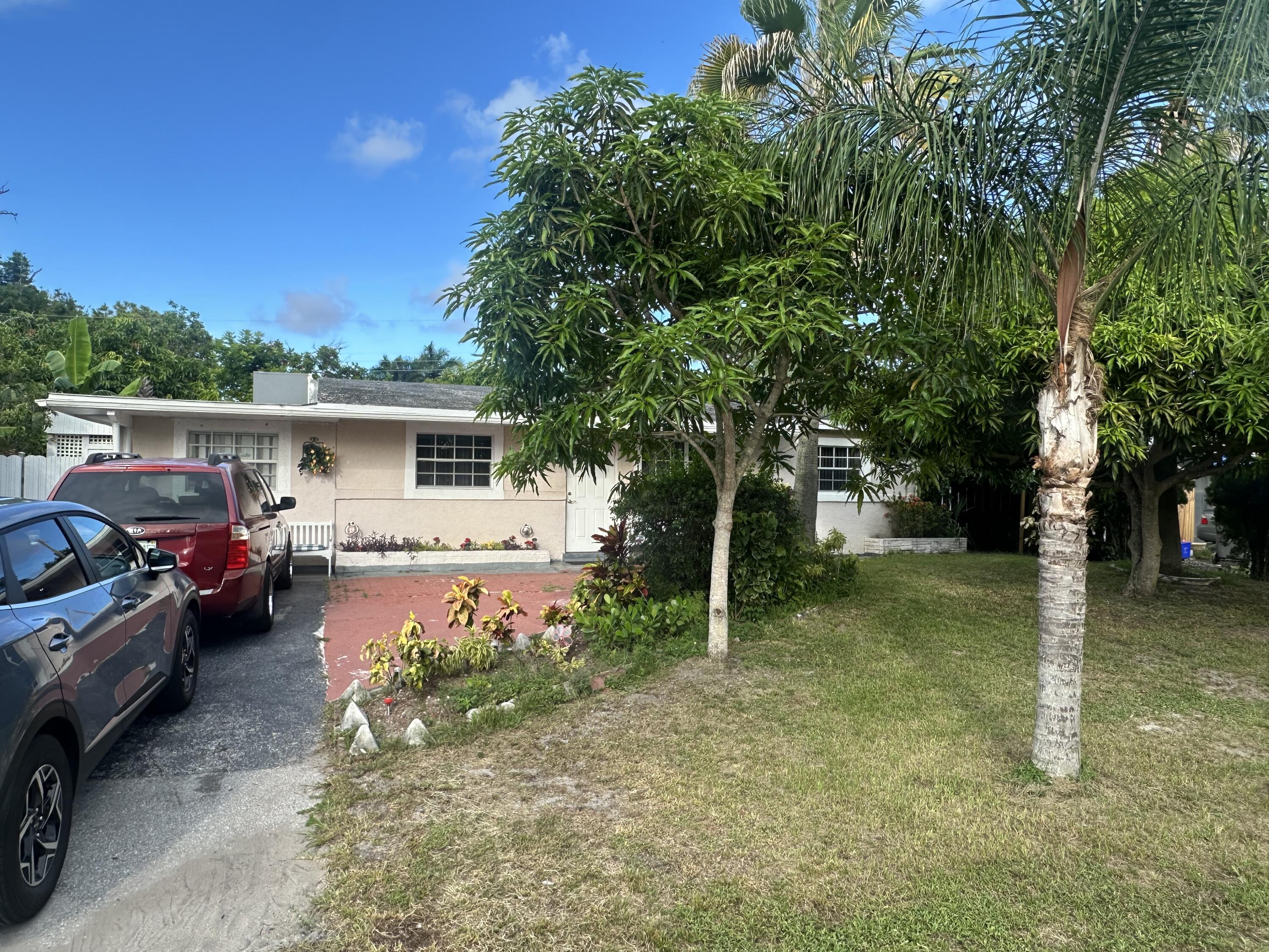 916 Caroline Avenue West Palm Beach, FL 33413 - Photo 2 of 14 a view of a house with a cars park side of a road