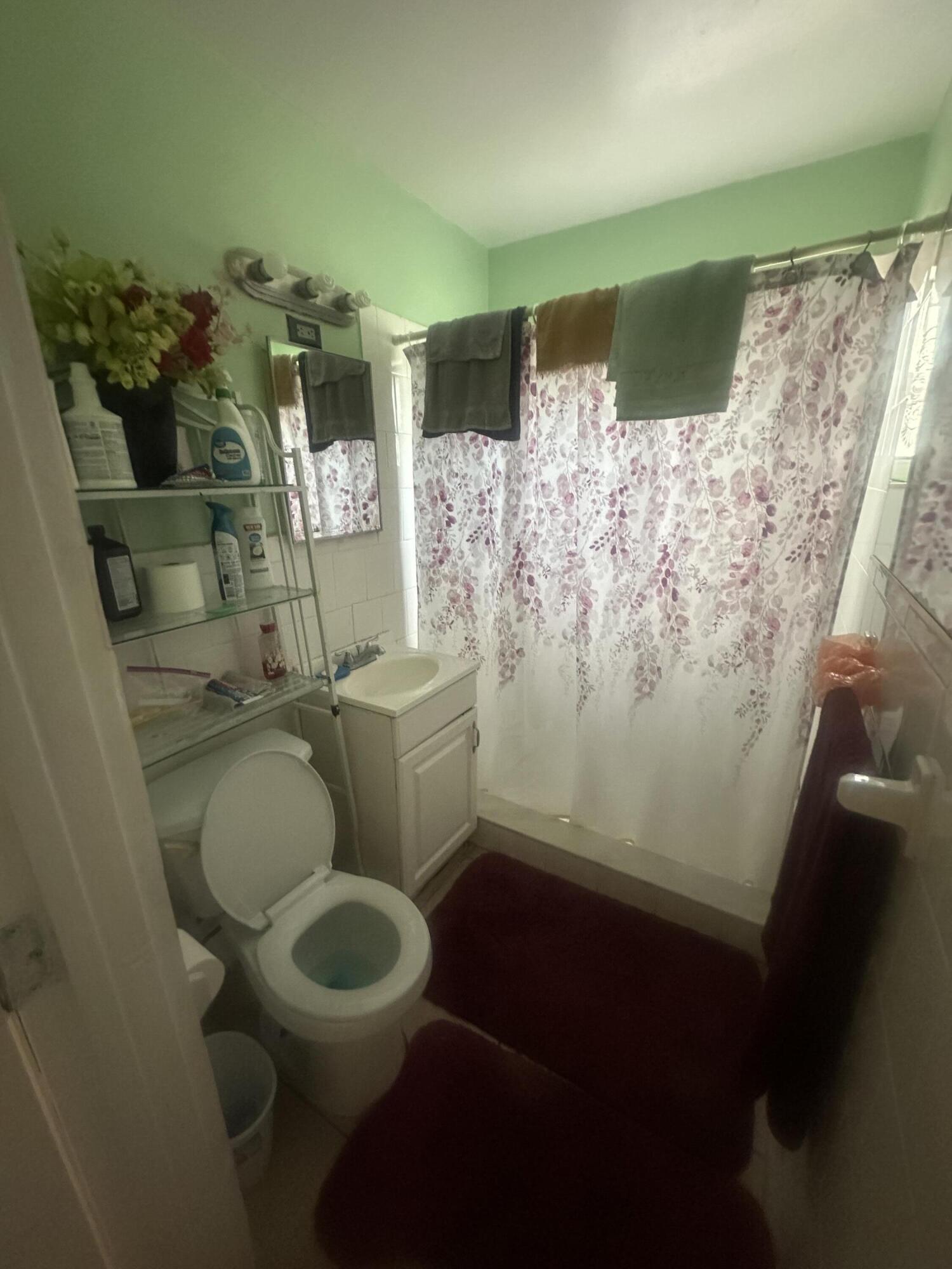 916 Caroline Avenue West Palm Beach, FL 33413 - Photo 8 of 14 a bathroom with a toilet and a shower curtain