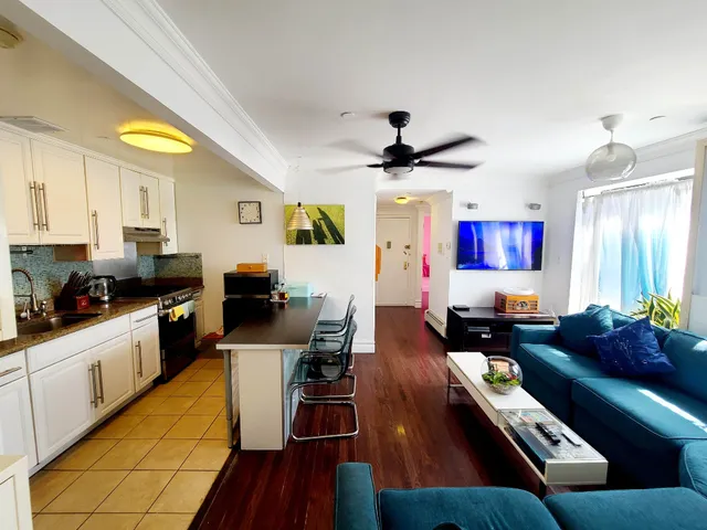 a living room with furniture kitchen view and a window