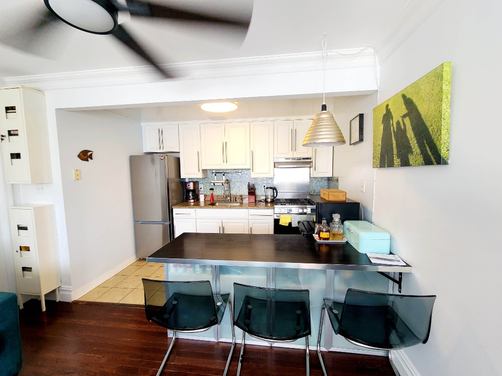 49-07 43rd Avenue, Unit 7F Queens, NY 11377 - Photo 2 of 16 a kitchen with stainless steel appliances a stove a refrigerator and wooden cabinets