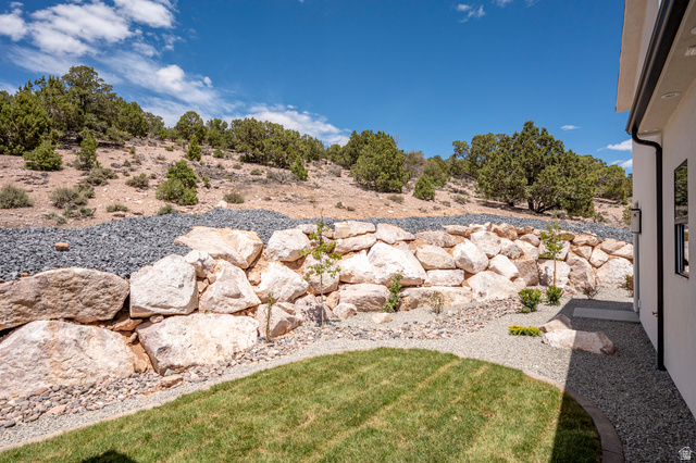 2862 South Mountain Rnch Road Cedar City, UT 84720 - Photo 57 of 64 Terraced landscaping featuring a stacked stone retaining wall, gravel beds, and a manicured lawn