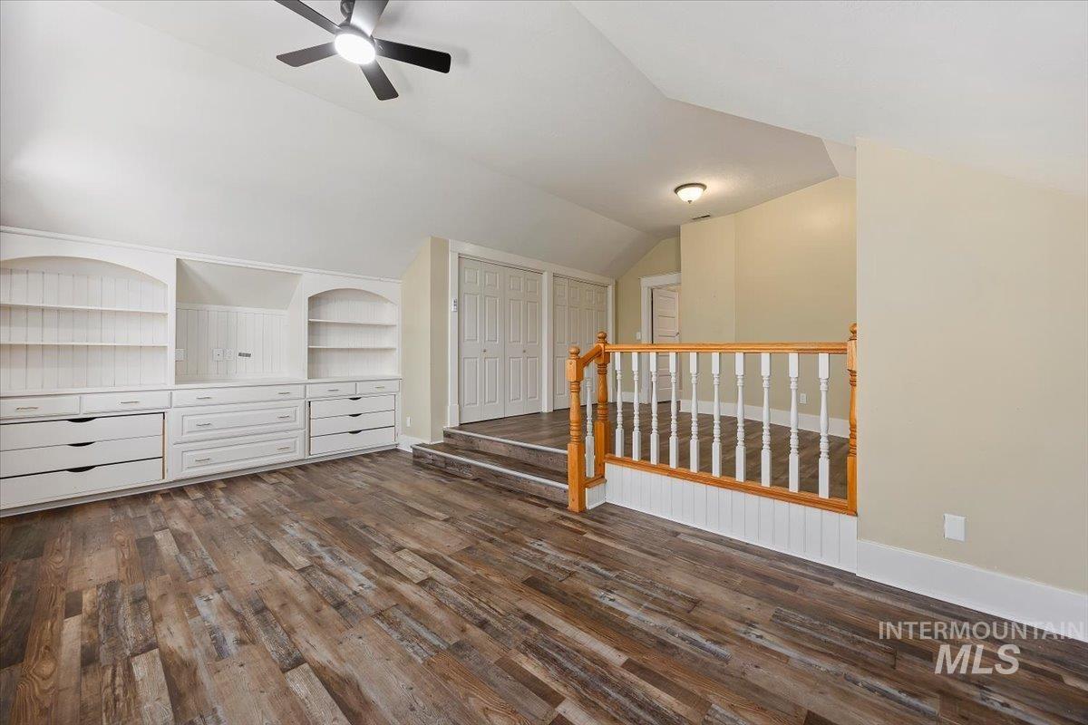 813 7th Street Rupert, ID 83350 - Photo 31 of 48 Spacious room featuring wood-finish flooring, a built-in entertainment center with shelving and drawers, a ceiling fan, and sloped ceilings