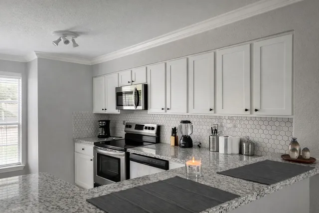 a kitchen with stainless steel appliances granite countertop a stove a sink a refrigerator a granite counter tops and white cabinets