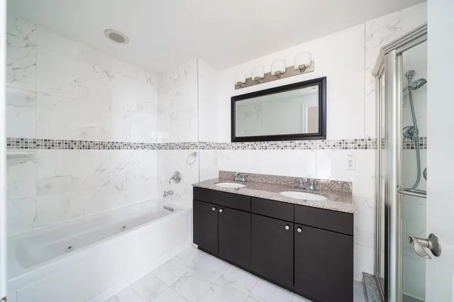 a bathroom with a bathtub shower sink vanity and mirror