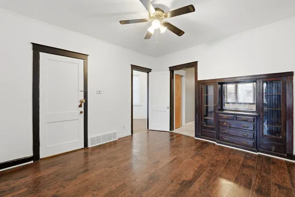 an empty room with wooden floor closet and windows