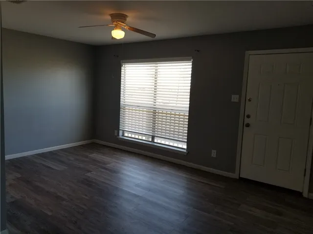 an empty room with wooden floor and windows