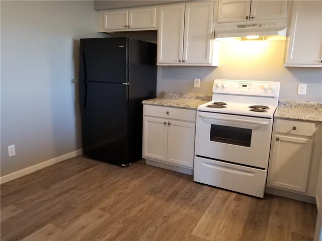a kitchen with a refrigerator stove and white cabinets