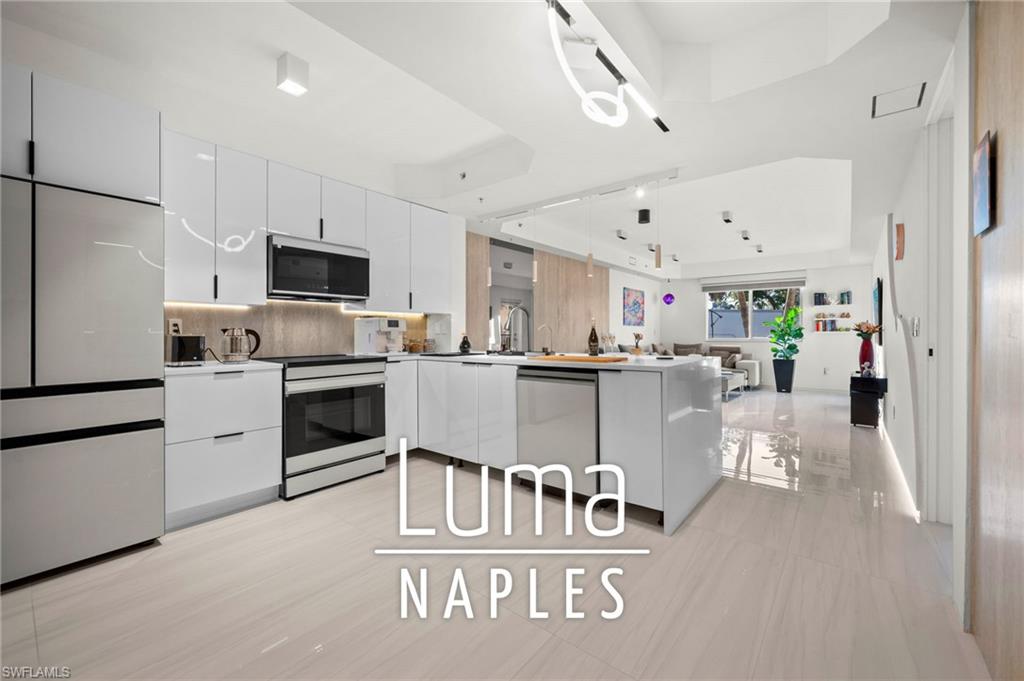 1100 Pine Ridge Road, Unit B103 Naples, FL 34108 - Photo 1 of 38 a kitchen with white cabinets and stainless steel appliances