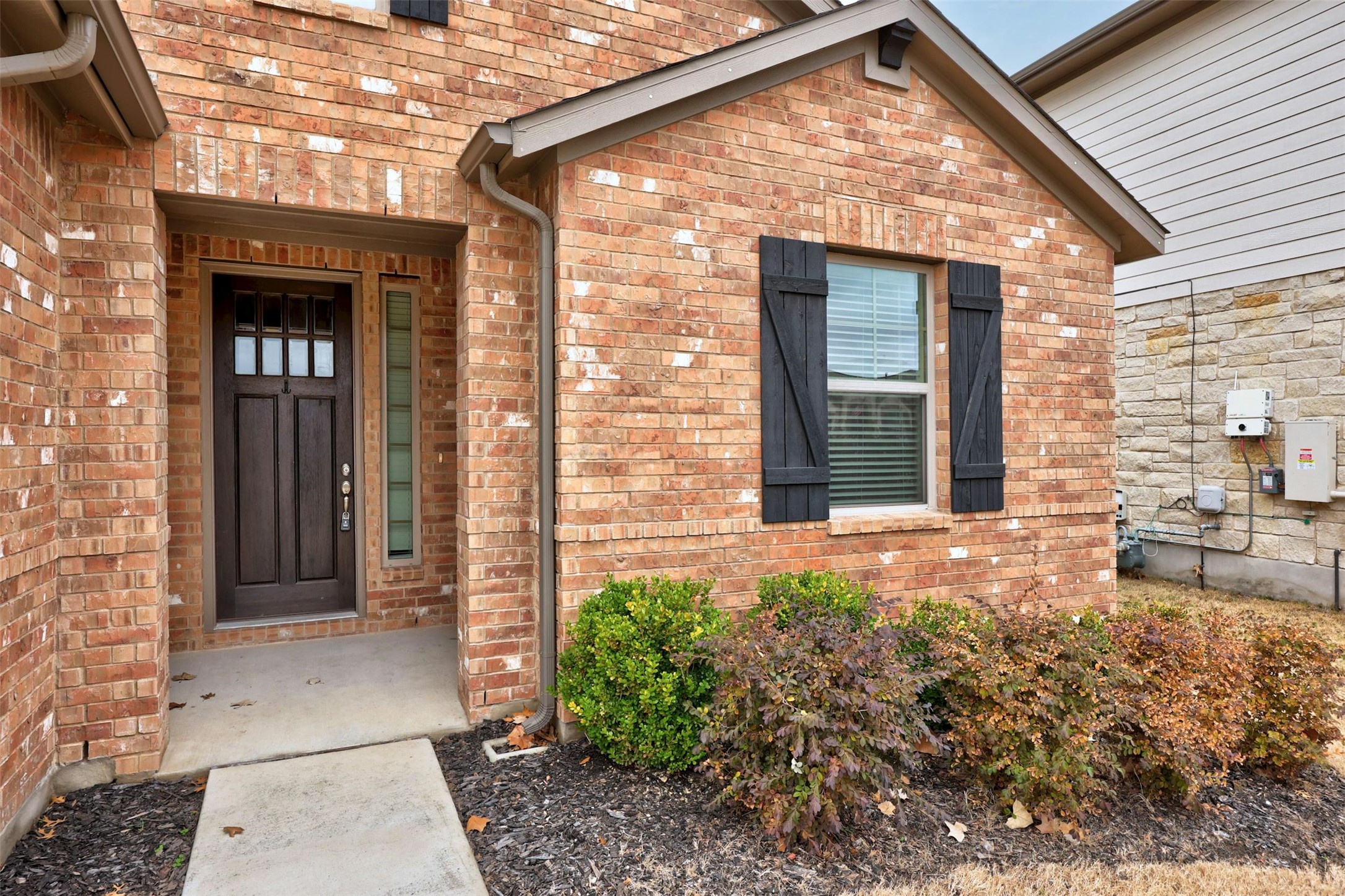 307 Simmental Loop Hutto, TX 78634 - Photo 4 of 34 Brick facade with striking black shutters and a prominent front entry.