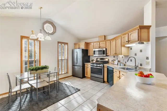 a kitchen with stainless steel appliances granite countertop a stove top oven a sink dishwasher and white cabinets with wooden floor
