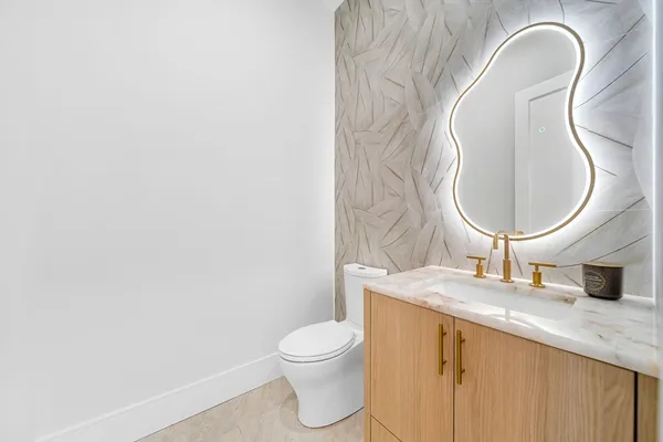 a bathroom with a granite countertop toilet sink and mirror