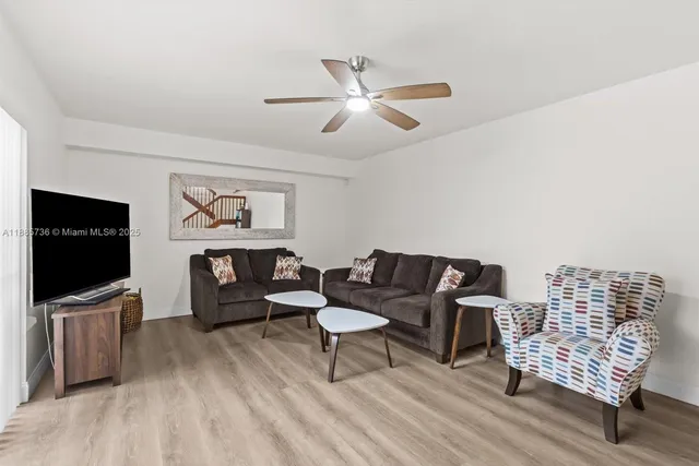 a living room with furniture a flat screen tv and wooden floor
