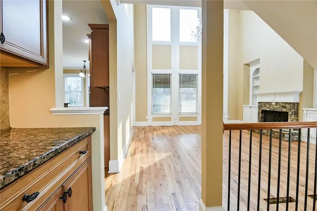 a view of an empty room with wooden floor fireplace and a window