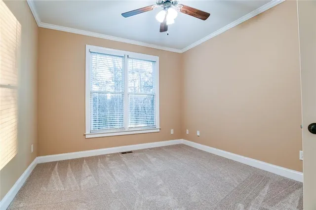 an empty room with chandelier fan and windows