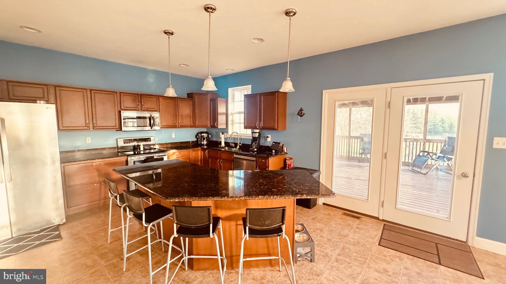 2295 Harney Road Littlestown, PA 17340 - Photo 31 of 37 a kitchen with stainless steel appliances granite countertop a stove a refrigerator a sink a dining table and chairs with wooden floor