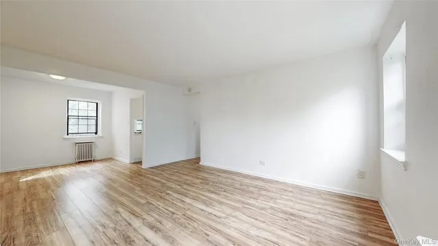 a view of an empty room with wooden floor and windows